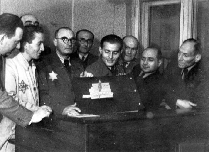 The photographer Mendel Grosman presenting an album of the Lodz ghetto to senior officials of the ghetto Judenrat.